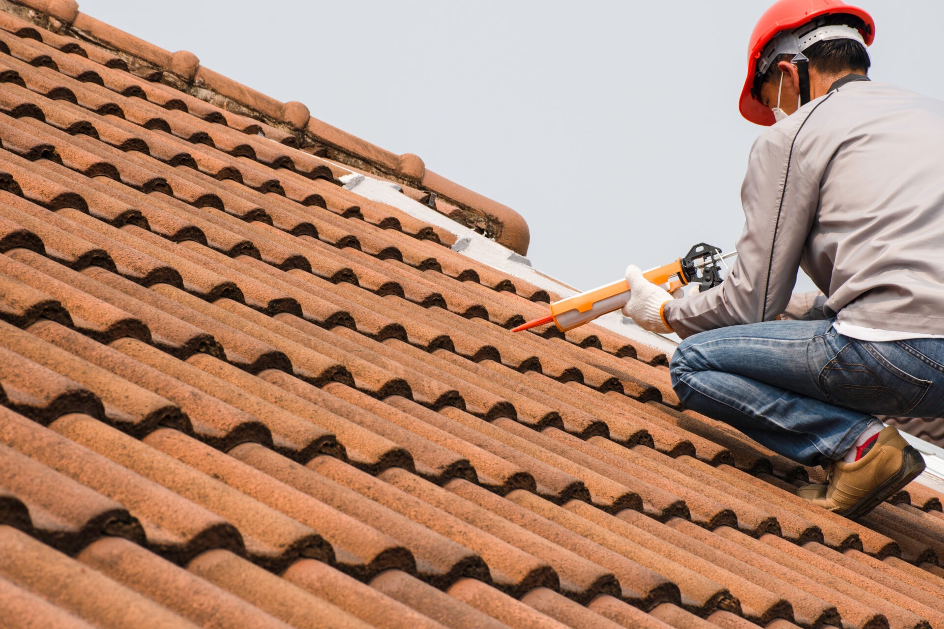 Roofer working on terracotta tiles during urgent roof leak checks