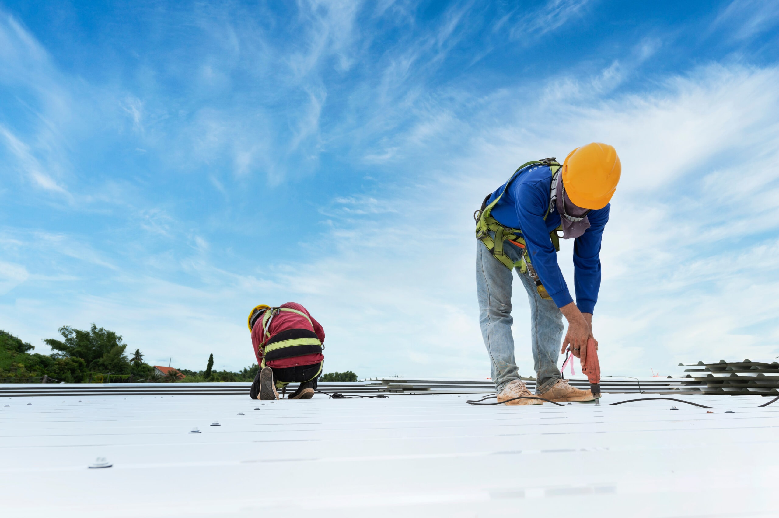 Two workers standing on a light-coloured metal roof