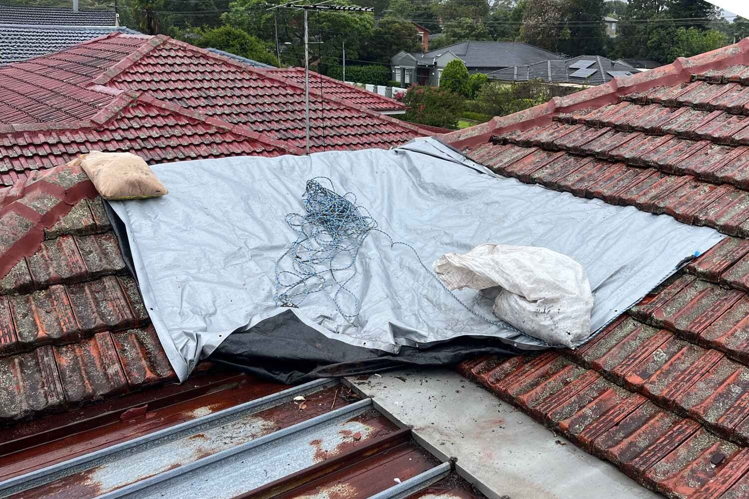 Temporary roof protection over a storm-damaged tiled roof